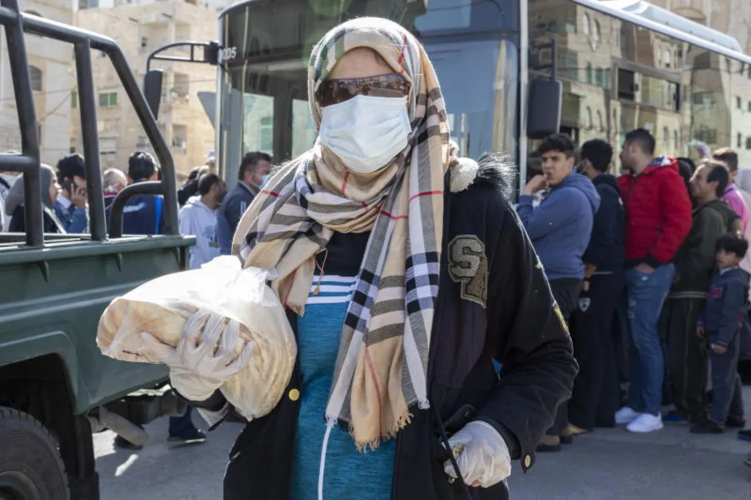 امرأة تحمل حصتها من الخبز الذي وزّعته أمانة عمّان (إ.ب.أ)