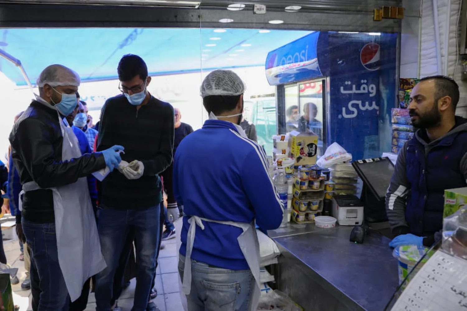 عاملون بمطعم في عمان يقدمون مطهّرات للزبائن (رويترز)