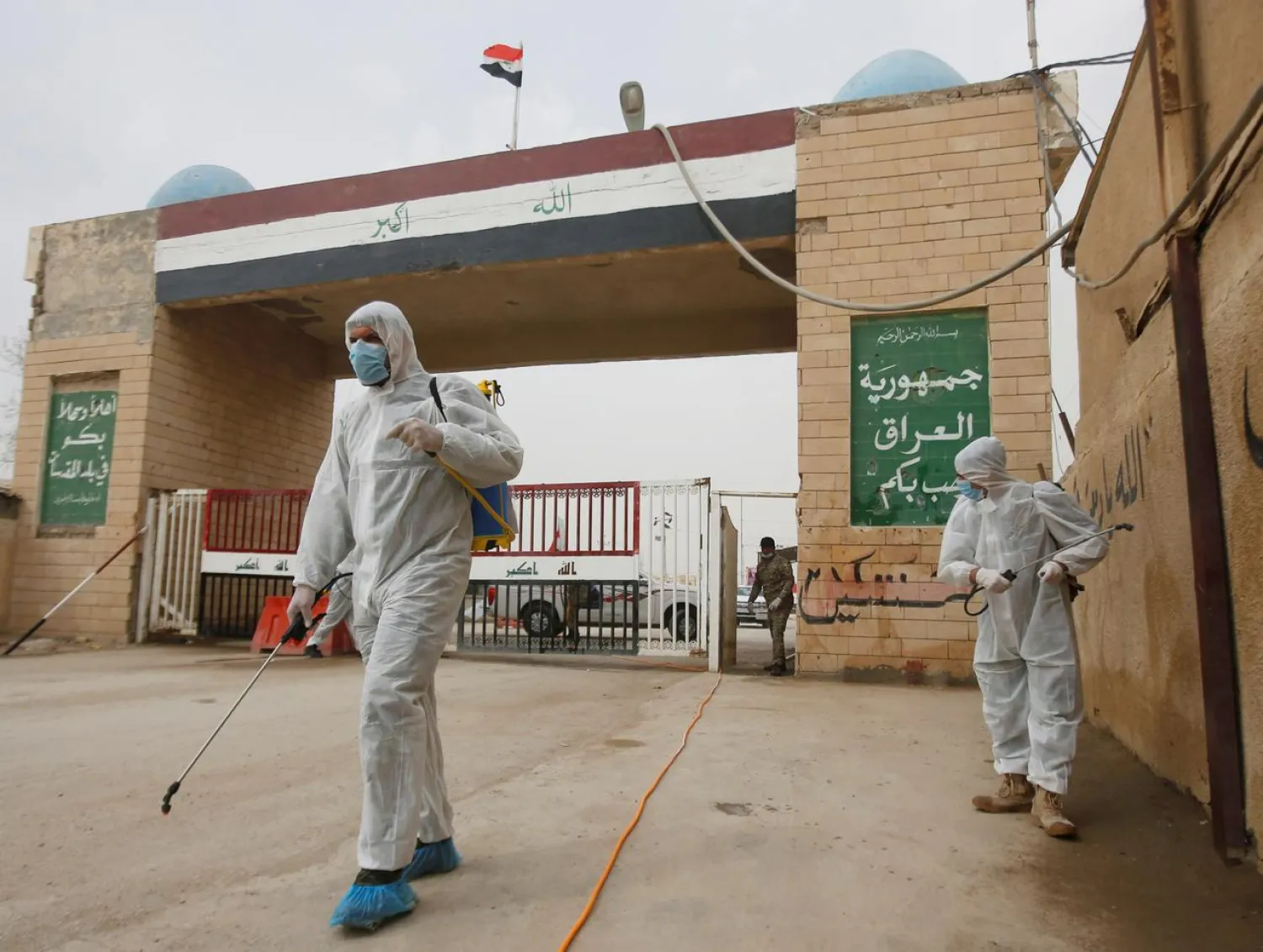 Workers in protective suits spray disinfectants near the gate of Shalamcha Border Crossing, after Iraq shut a border crossing to travelers between Iraq and Iran, Iraq March 8, 2020. REUTERS/Essam al-Sudani