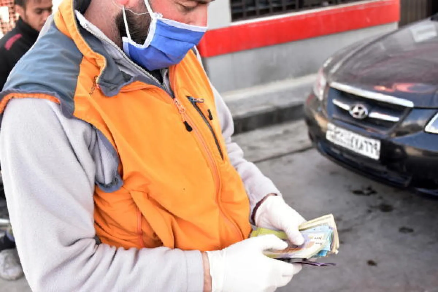 عامل بمحطة وقود في دمشق يرتدي القناع والقفازات الطبية لحماية نفسه من فيروس كورونا (الشرق الأوسط)