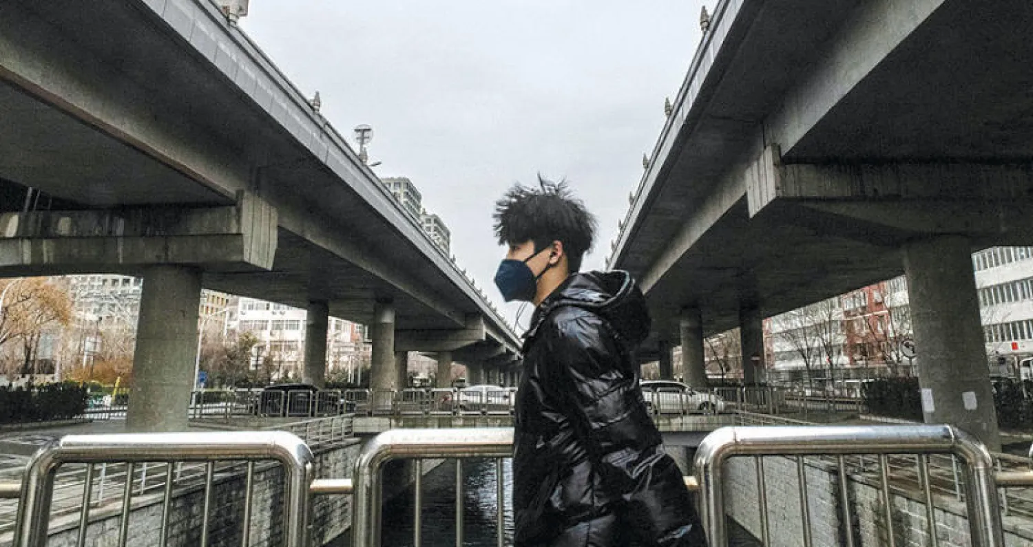 شاب في شارع شبه خالٍ من المارة في بكين الشهر الماضي (نيويورك تايمز)