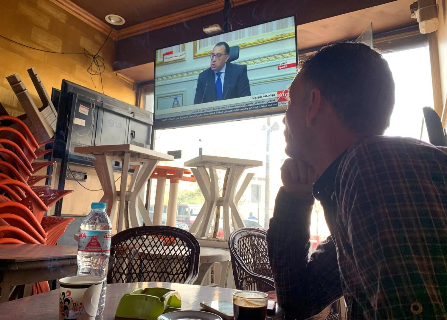 An Egyptian citizen watches PM Mostafa Madbouly on TV, at an almost empty coffee shop, as Egypt ramps up its efforts to slow down the spread of COVID-19 in Cairo, Egypt, March 24, 2020. (Reuters)