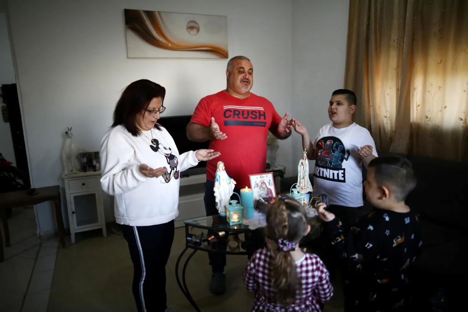 The Palestinian Sara family pray together while observing a partial lockdown to curb the spread of the coronavirus disease (COVID-19) at their home in Jerusalem March 25, 2020. REUTERS/Ammar Awad
