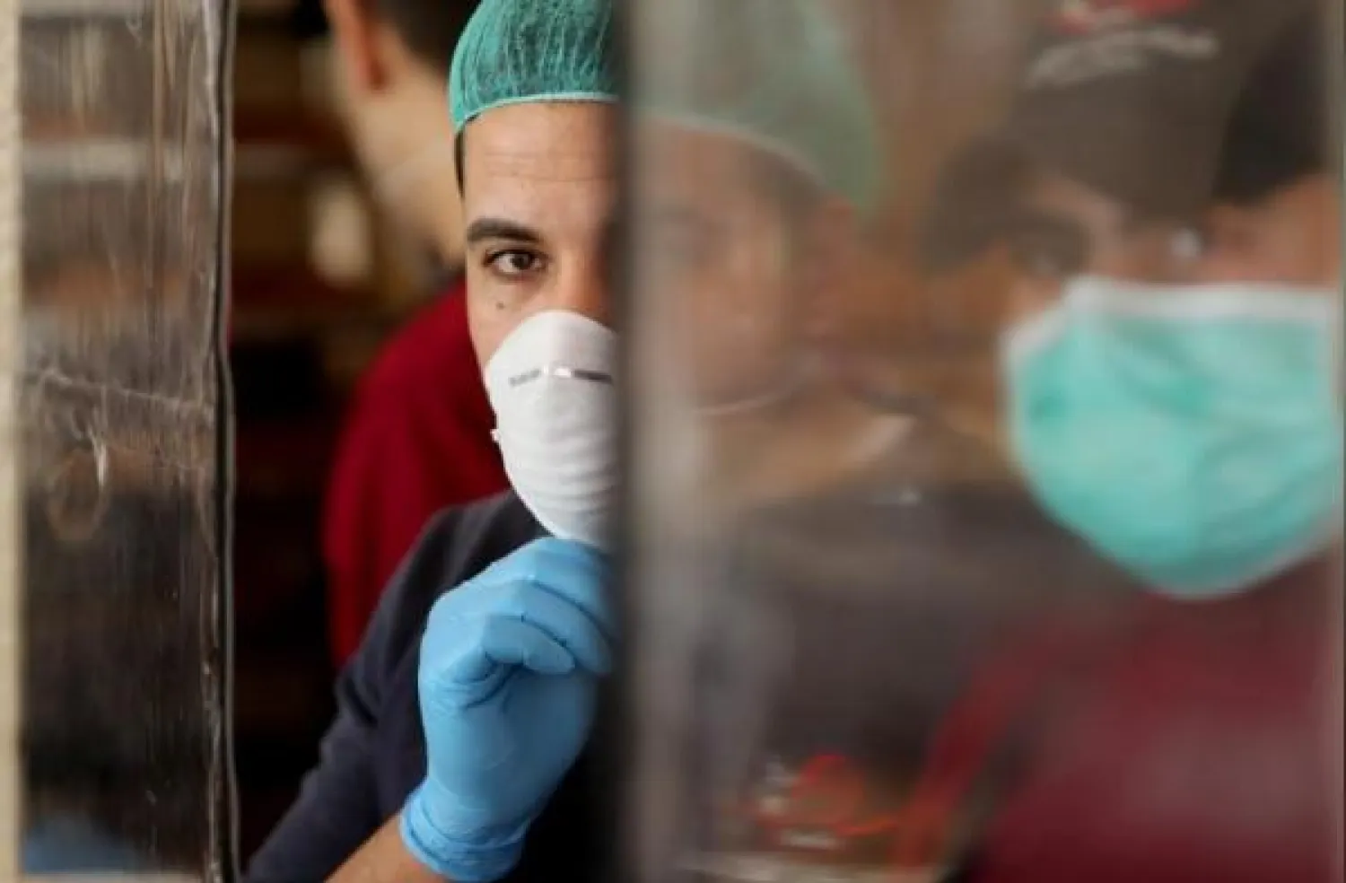 رجلان يضعان كمامتين للوقاية من خطر الإصابة بفيروس كورونا في غزة (رويترز)