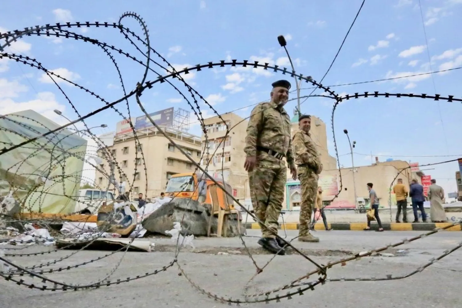 Iraqi policemen stand behind barbed wire during ongoing anti-government demonstrations in Baghdad's Tahrir Square (AFP)

