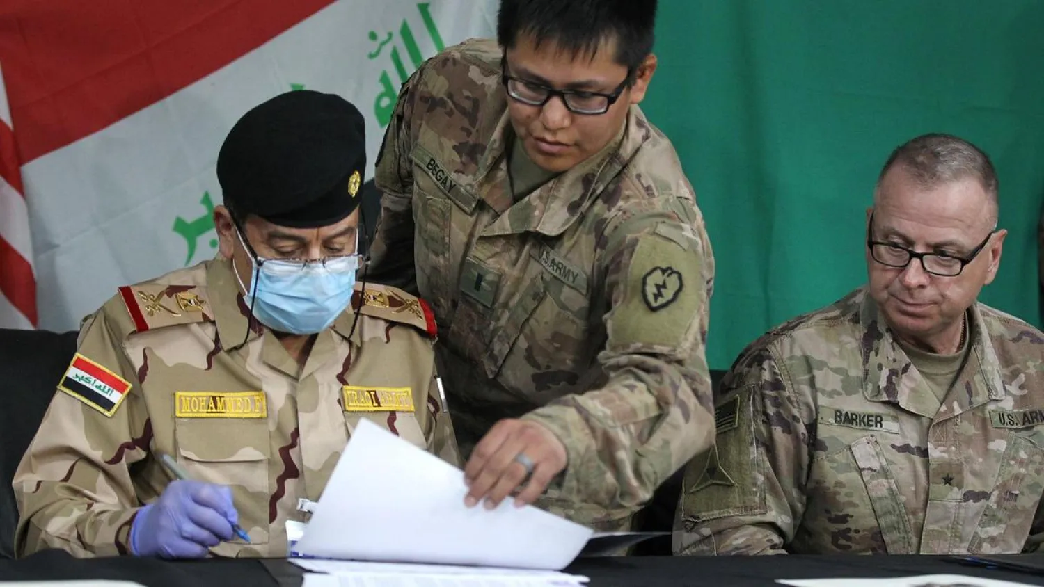 US and Iraqi officials signing a document during a pullout ceremony at the Qayyarah air base on March 26, 2020. (AFP)