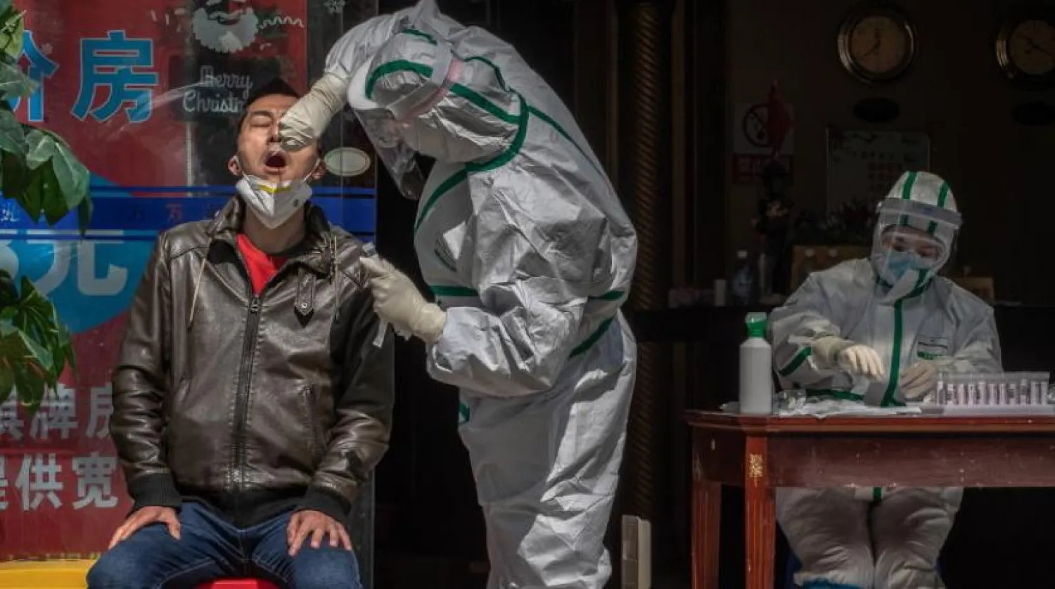 Koruyucu kıyafet giyen bir doktor sokakta kontrol yapıyor (AFP)