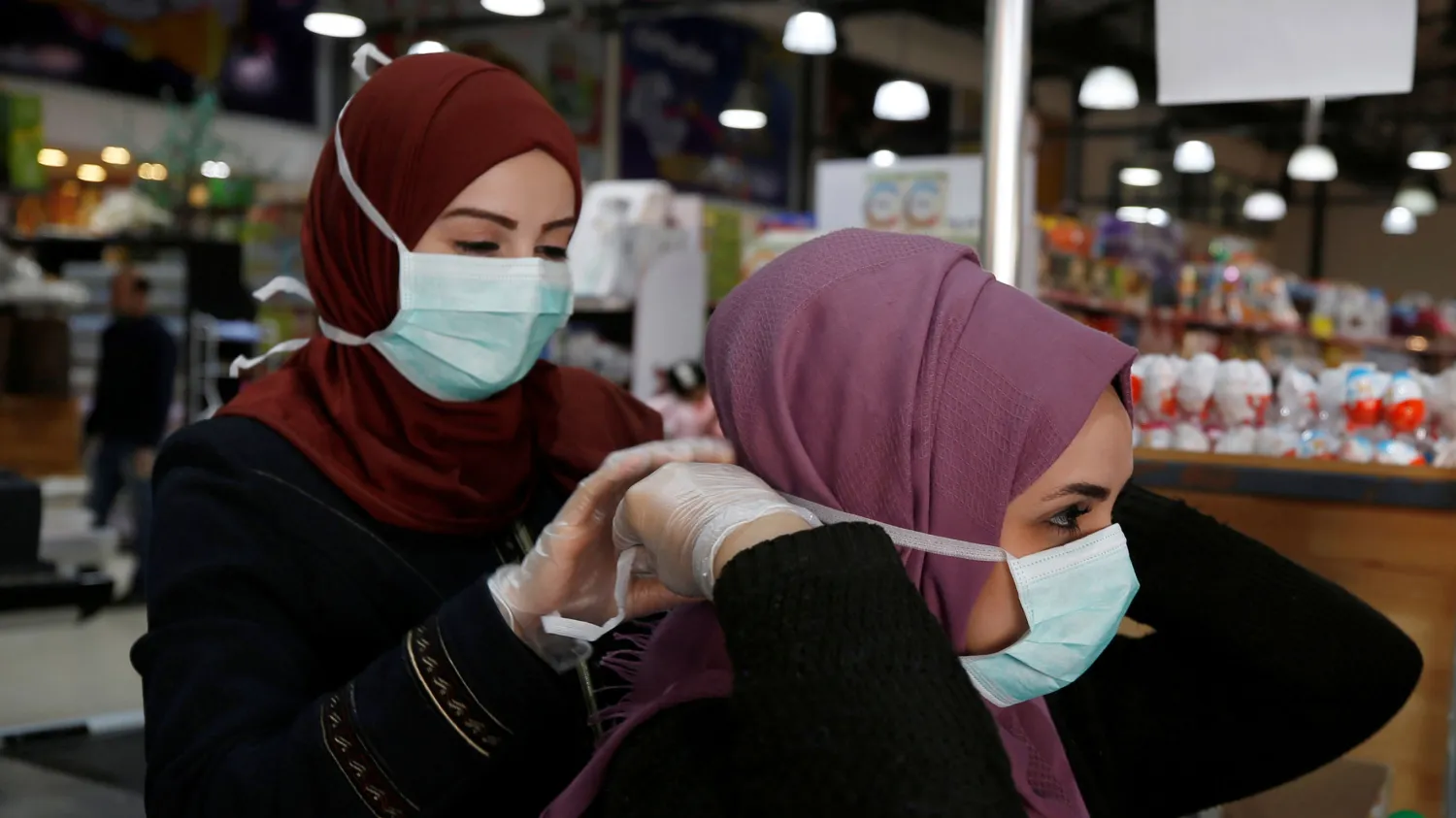 A woman helps her colleague put on a mask amid coronavirus precautions in a supermarket in Gaza City, Gaza, March 8, 2020. Reuters

