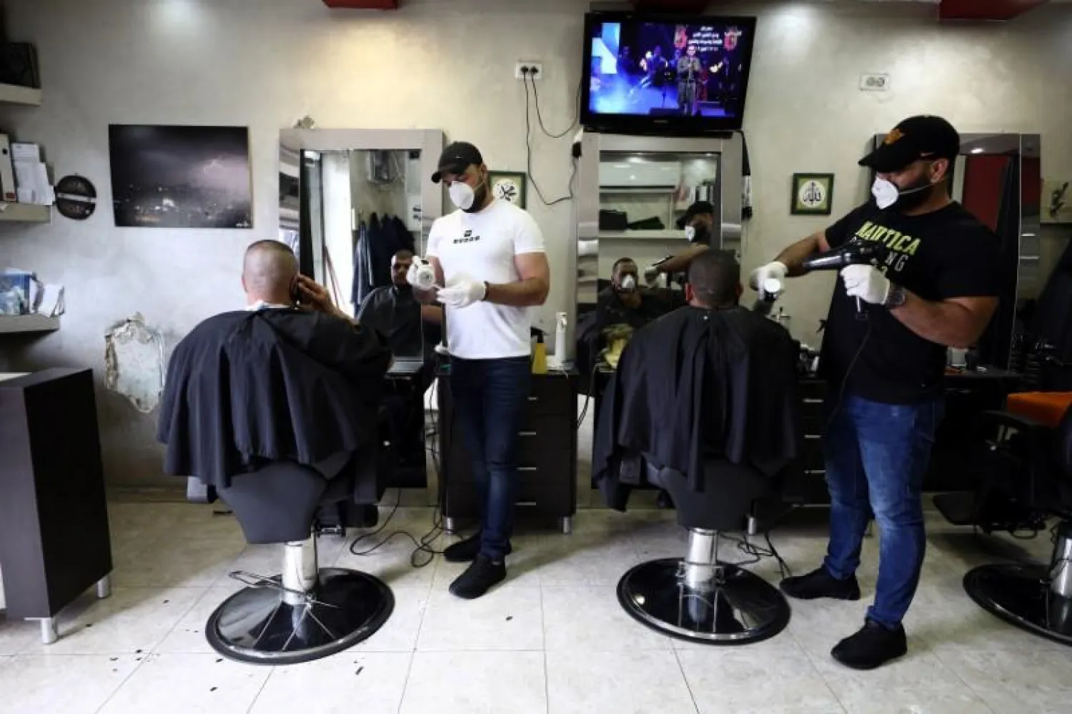 People get their hair cut in a barber shop in Jerusalem as workers wear face masks as a protection against coronavirus March 18, 2020. REUTERS/Ammar Awad
