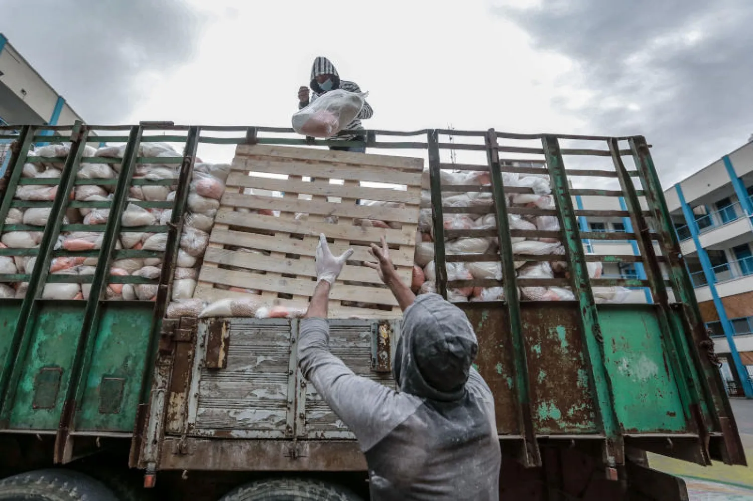 موظفون فلسطينيون في (الأونروا) يعملون في توزيع المساعدات الغذائية في غزة (د.ب.أ)
