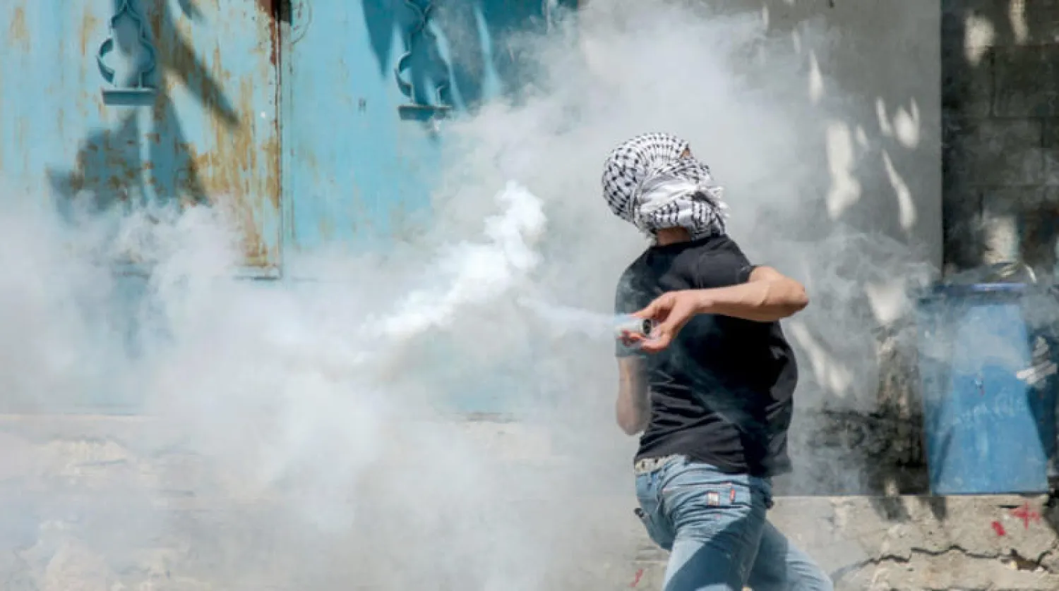 فلسطيني يعيد إلقاء عبوة مسيلة للدموع في كفر قدوم بالضفة الغربية خلال مواجهات أمس مع القوات الإسرائيلية (د.ب.أ)