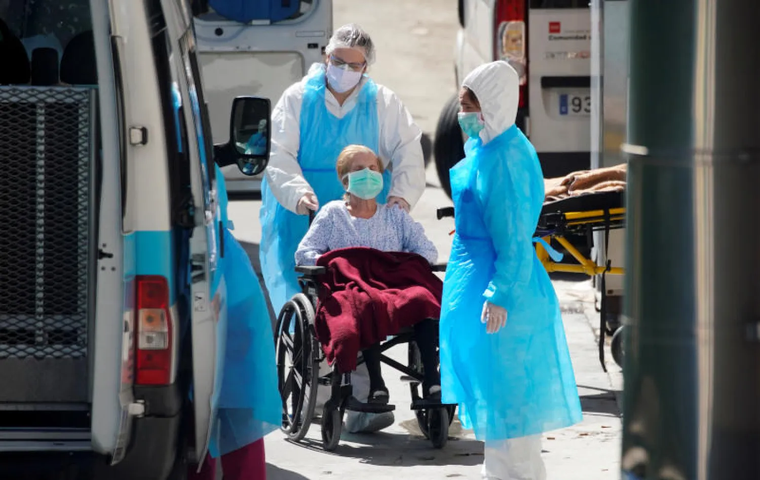 مسعفون يدفعون كرسياً متحركاً لمصاب بفيروس «كورونا» في ليجانيس بالقرب من مدريد (رويترز)