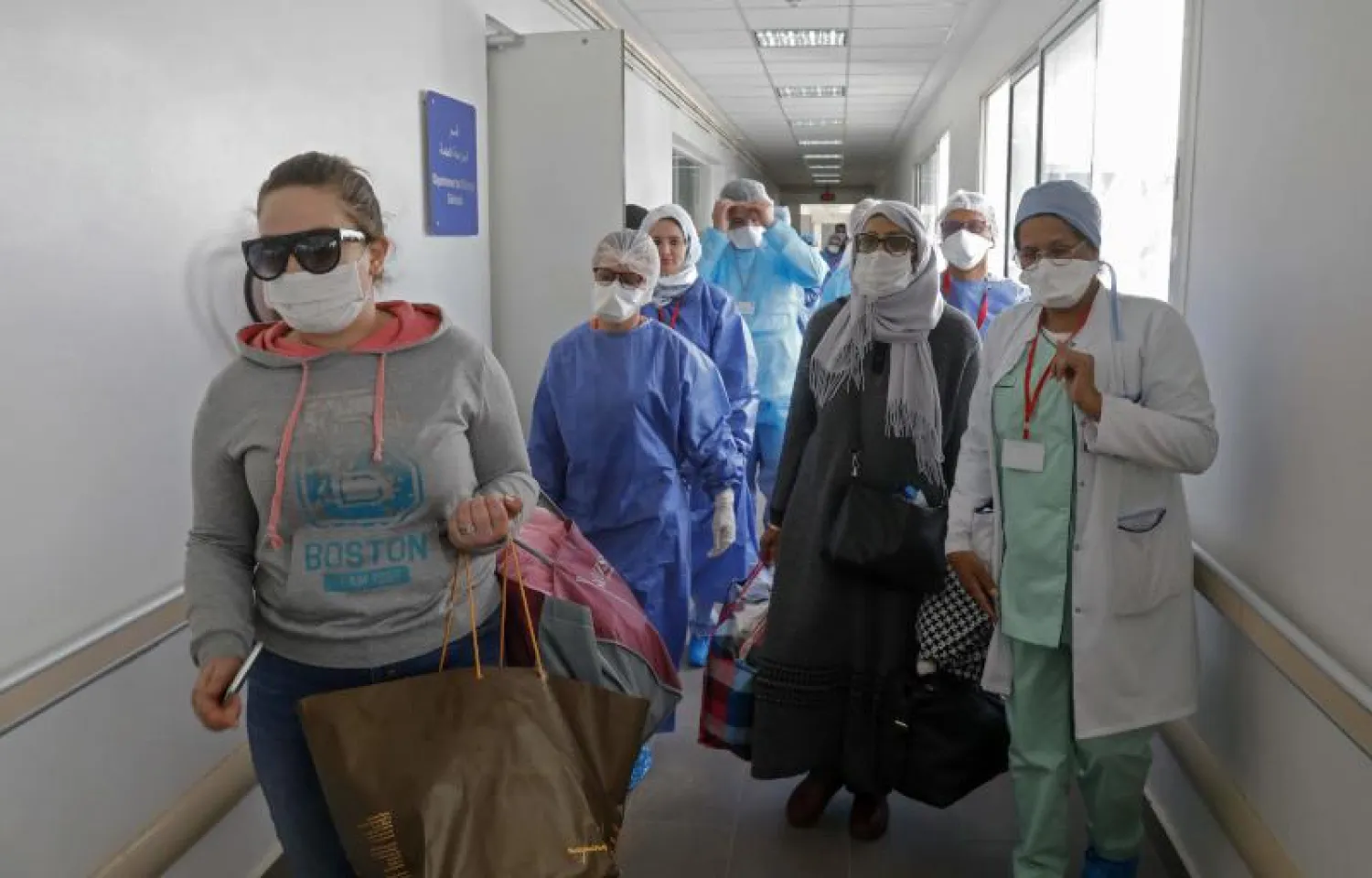 مرضى مغربيون تعافوا من فيروس كورونا يغادرون المستشفى بصحبة الطاقم الطبي في سلا (أ.ف.ب)