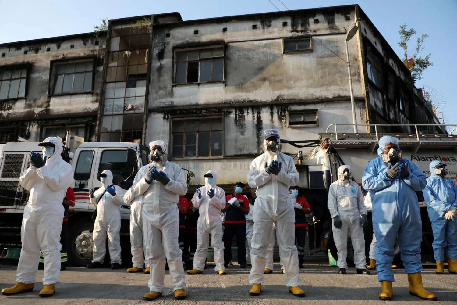 Workers wearing protective suits pray before a disinfection operation, during the movement control order due to the outbreak of the coronavirus disease (COVID-19), in Kuala Lumpur, Malaysia April 1, 2020. REUTERS/Lim Huey Teng