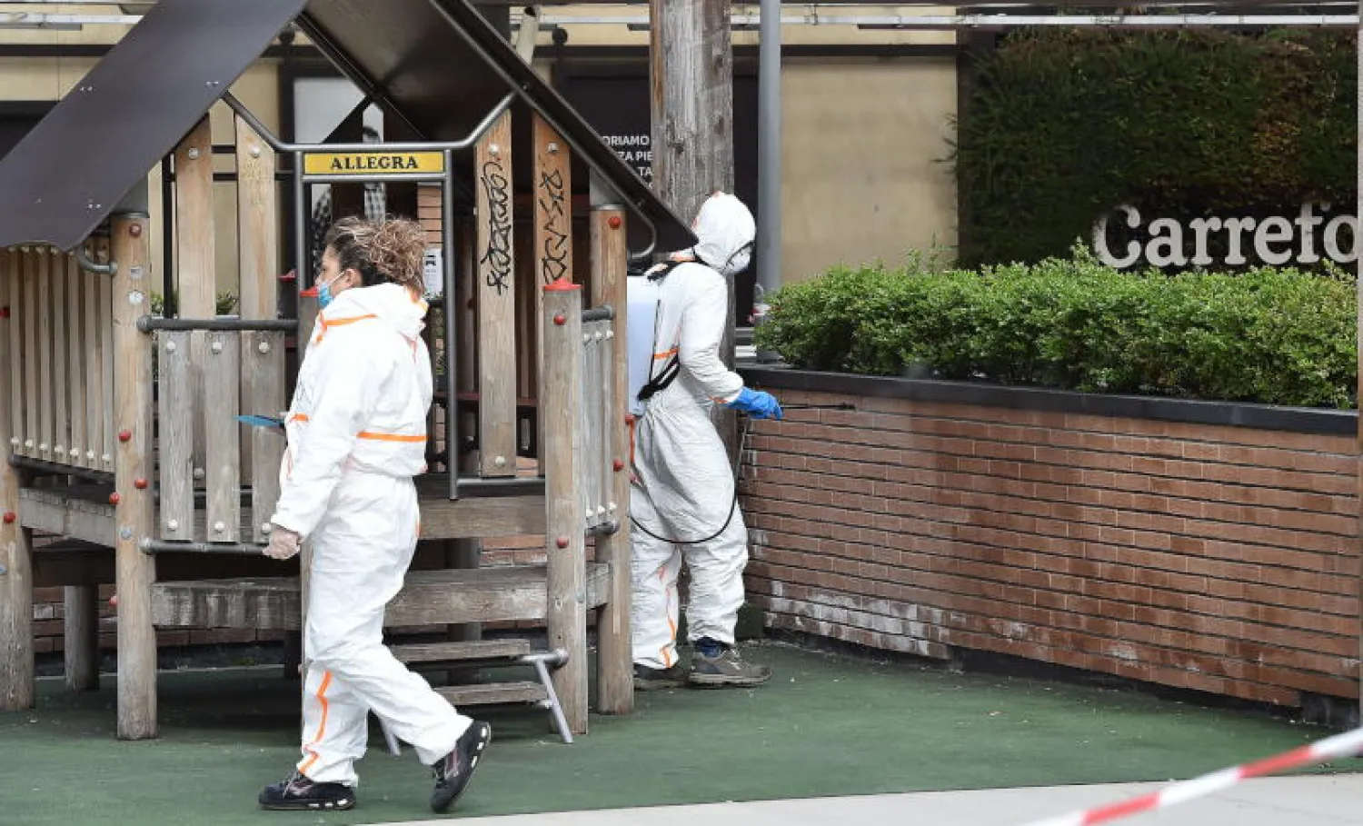 مسؤول يرش المطهرات بالقرب من أحد المتاجر الإيطالية (أ.ف.ب)