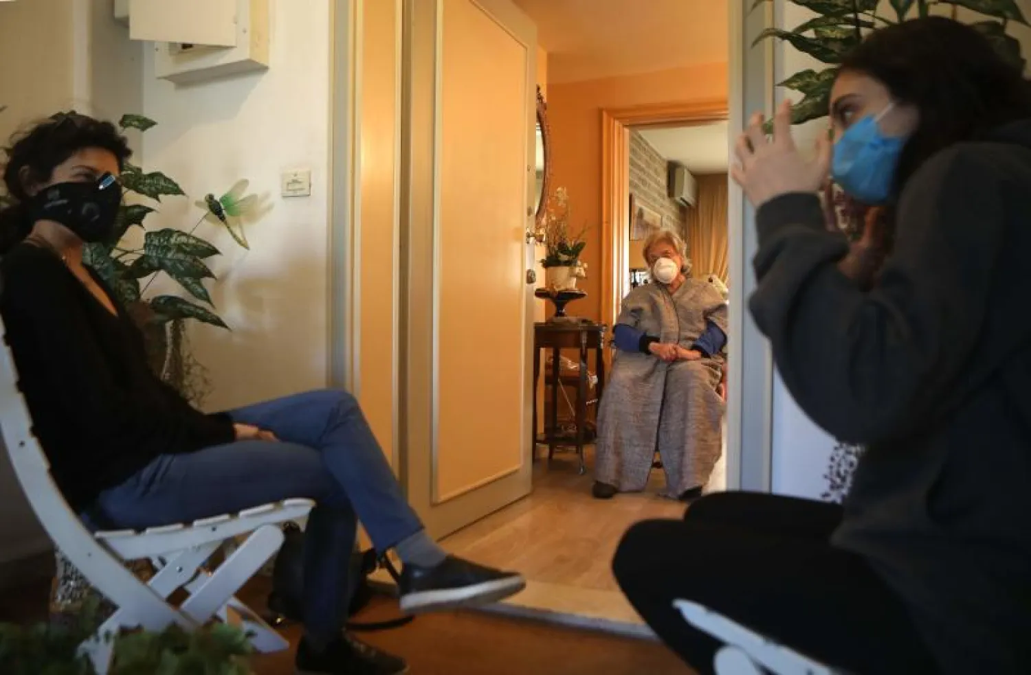 فتاتان لبنانيتان تجلسان متفرقتين تاركتين مسافة في أثناء زيارة والدتهما بالعاصمة بيروت (أ.ف.ب)