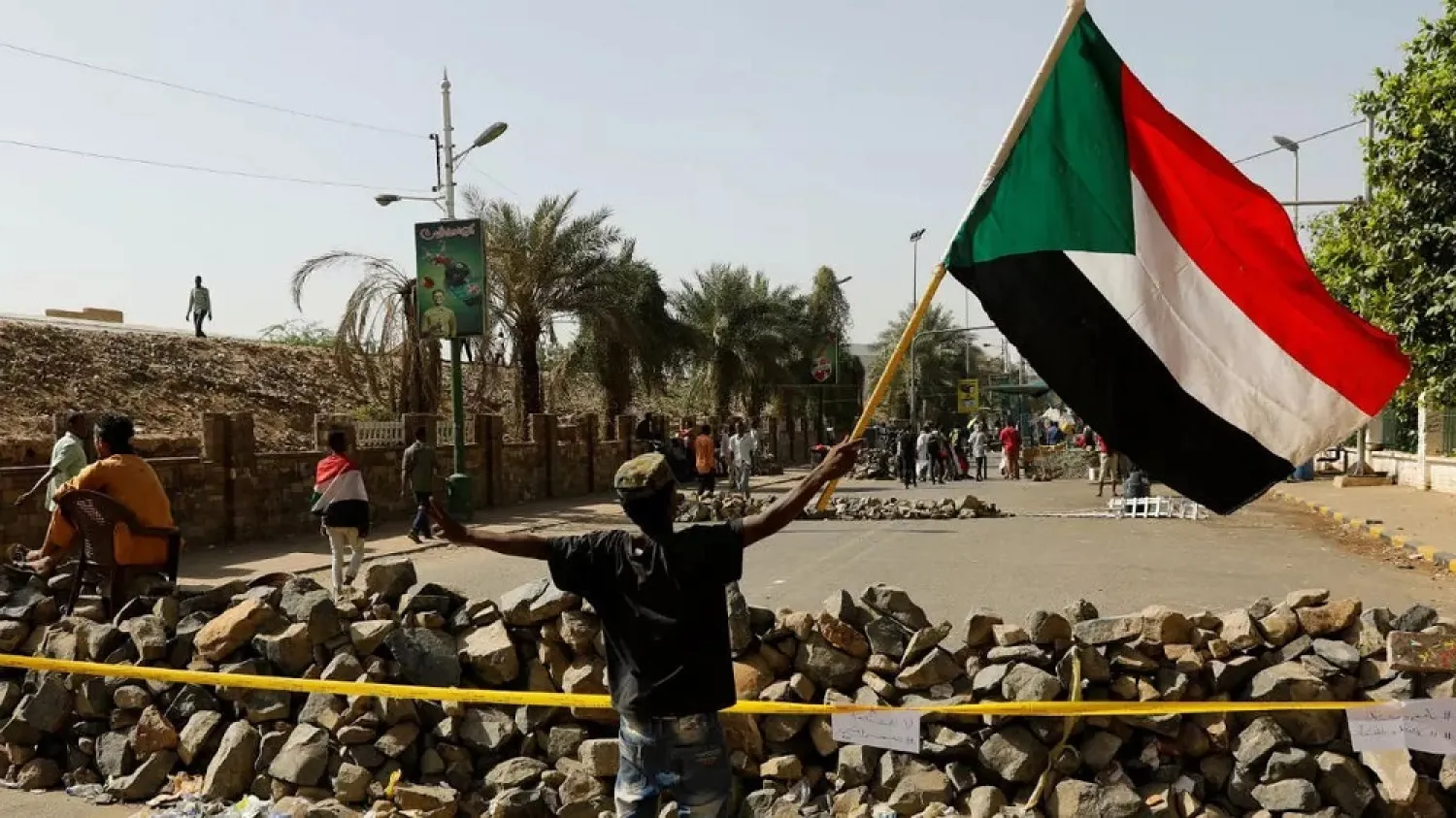 A Sudanese protester waves a national flag in front of a barricade on a road leading to the defense ministry compound in Khartoum, April 30, 2019. (Reuters)