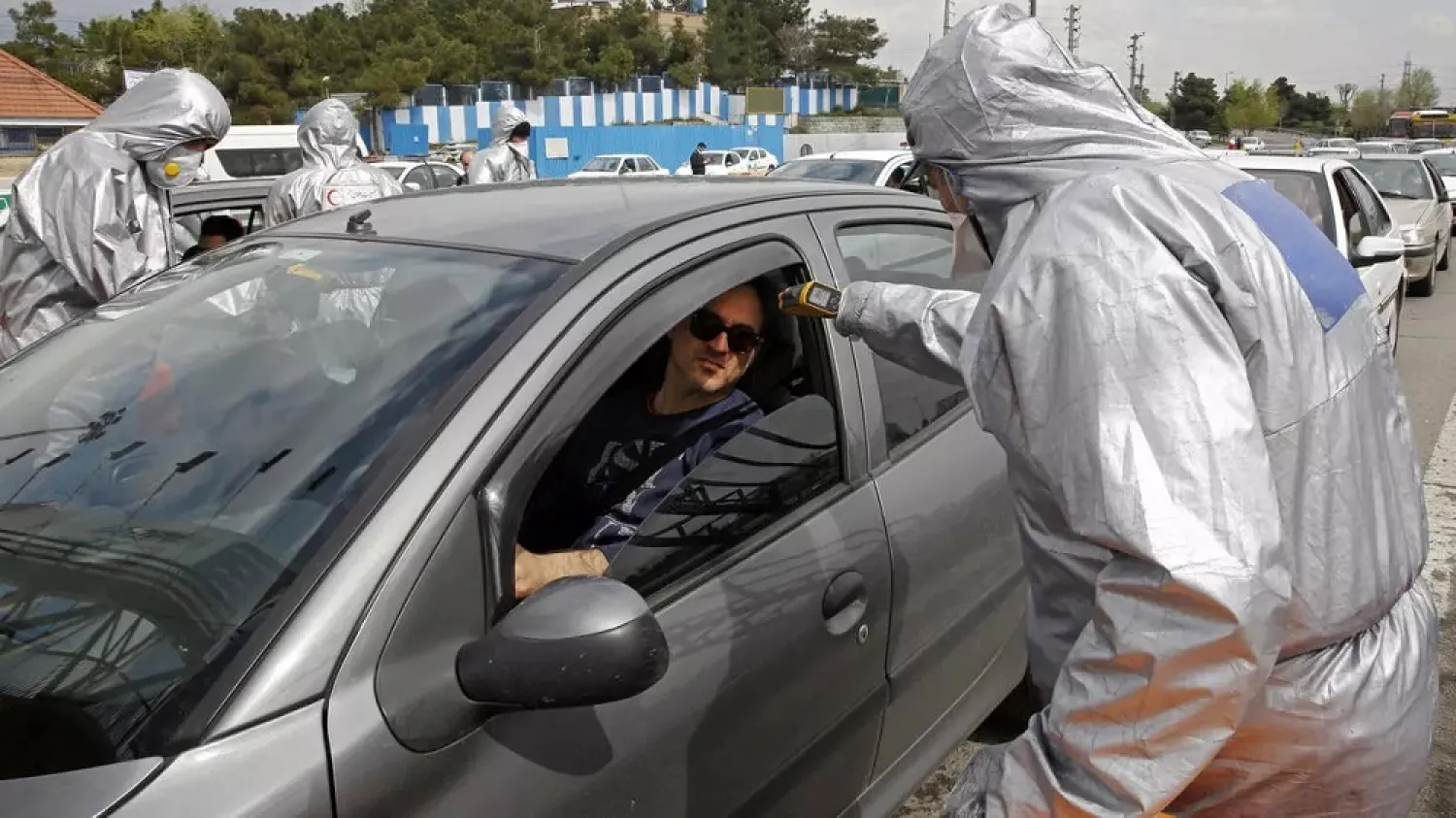 Red Crescent members test people for coronavirus symptoms, as Iranian police blocked Tehran to Alborz highway to check every car. (AFP)