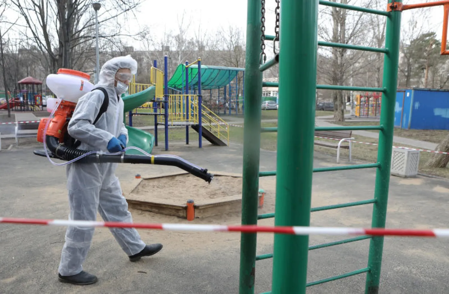 عامل يرتدي معدات واقية يرش مطهراً أثناء عمليات التعقيم في موسكو (رويترز)