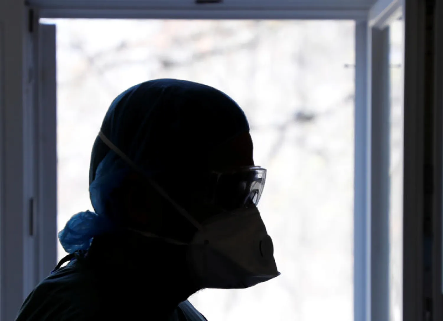 أحد أعضاء طاقم طبي يضع قناعاً واقياً أثناء معالجة مريض «كوفيد - 19» بمستشفى في برلين (رويترز)