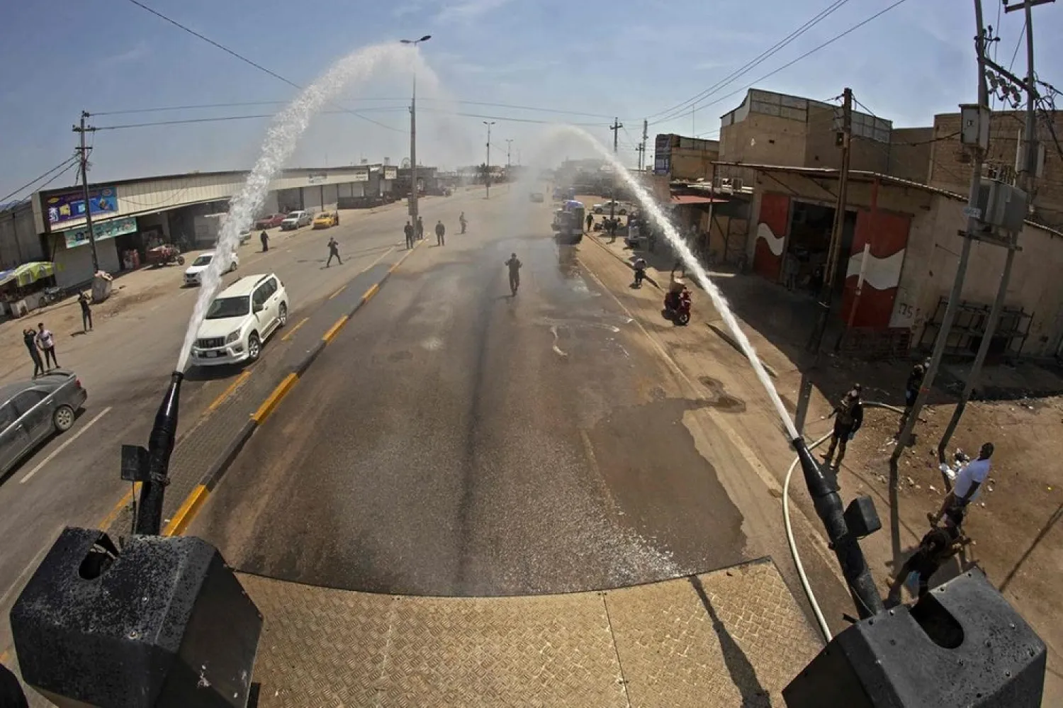 Iraqis use an anti-riot water-cannon vehicle to spray disinfecting liquid in the streets of the center of the southern city of Basra. (AFP)