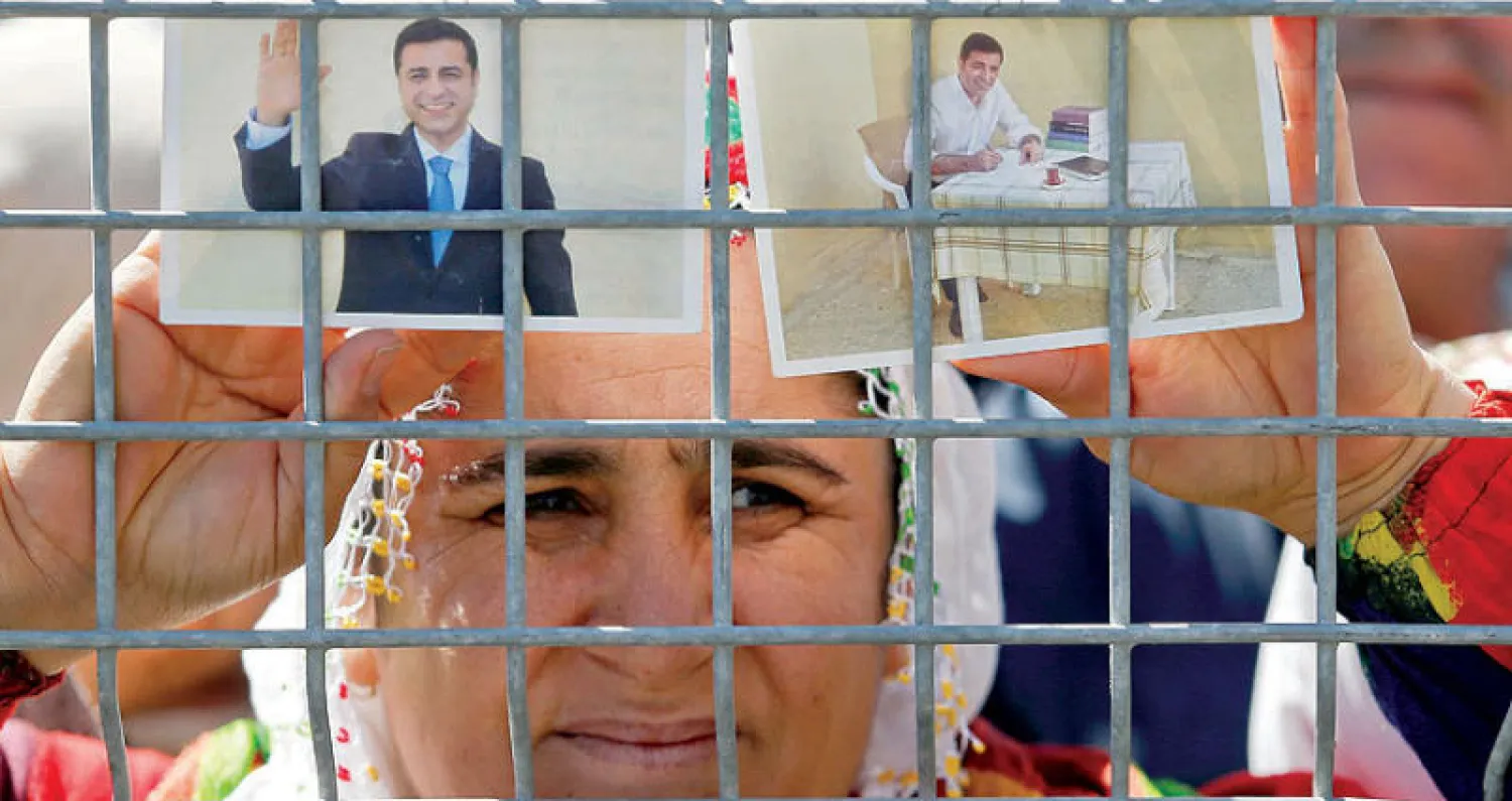 تركية تعرض صورة للرئيس السابق لحزب الشعوب الديمقراطي السجين (رويترز)