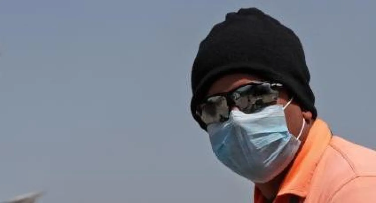 موظف في مطار الدوحة يرتدي كمامة واقية (أ.ف.ب)