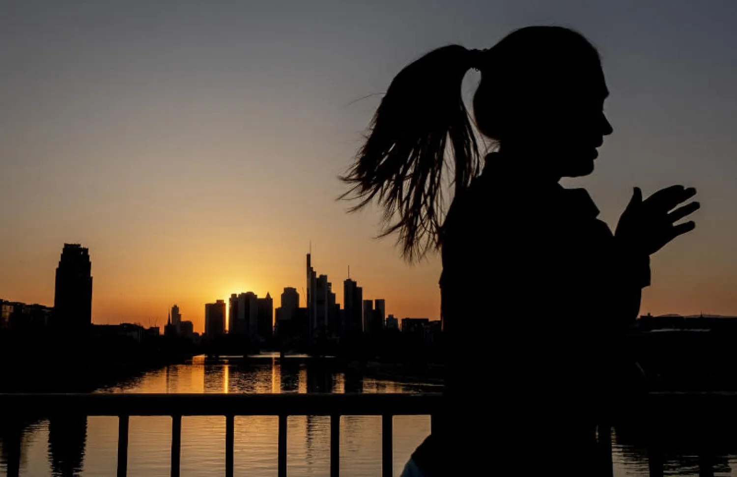 امرأة تجري فوق جسر في فرانكفورت بألمانيا (أ.ب)