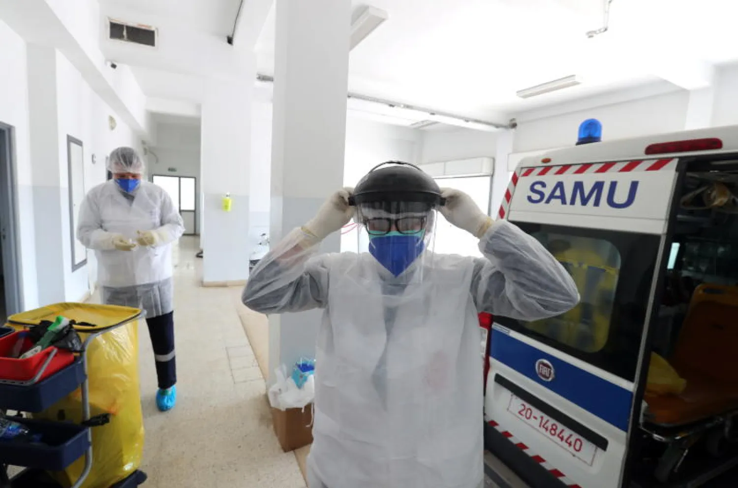 طبيب تونسي يرتدي الملابس الواقية قبل التوجه لعلاج مصاب بكورونا (إ.ب.أ)