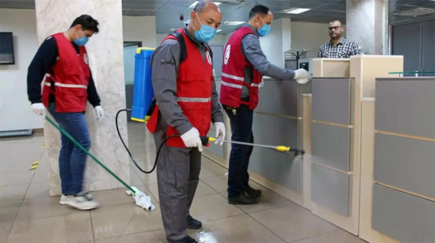 أعضاء في الهلال الأحمر الليبي يقومون بتعقيم أحد المكاتب الحكومية بمصراته (غرب) (رويترز)