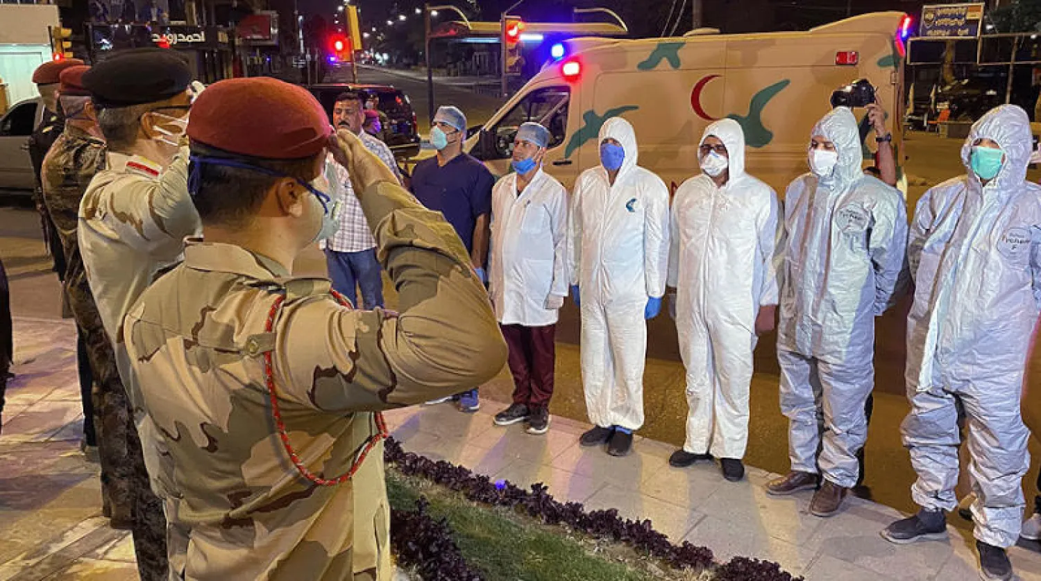 ضباط في الجيش العراقي يؤدون التحية لأطباء وممرضين في بغداد (أ.ب)