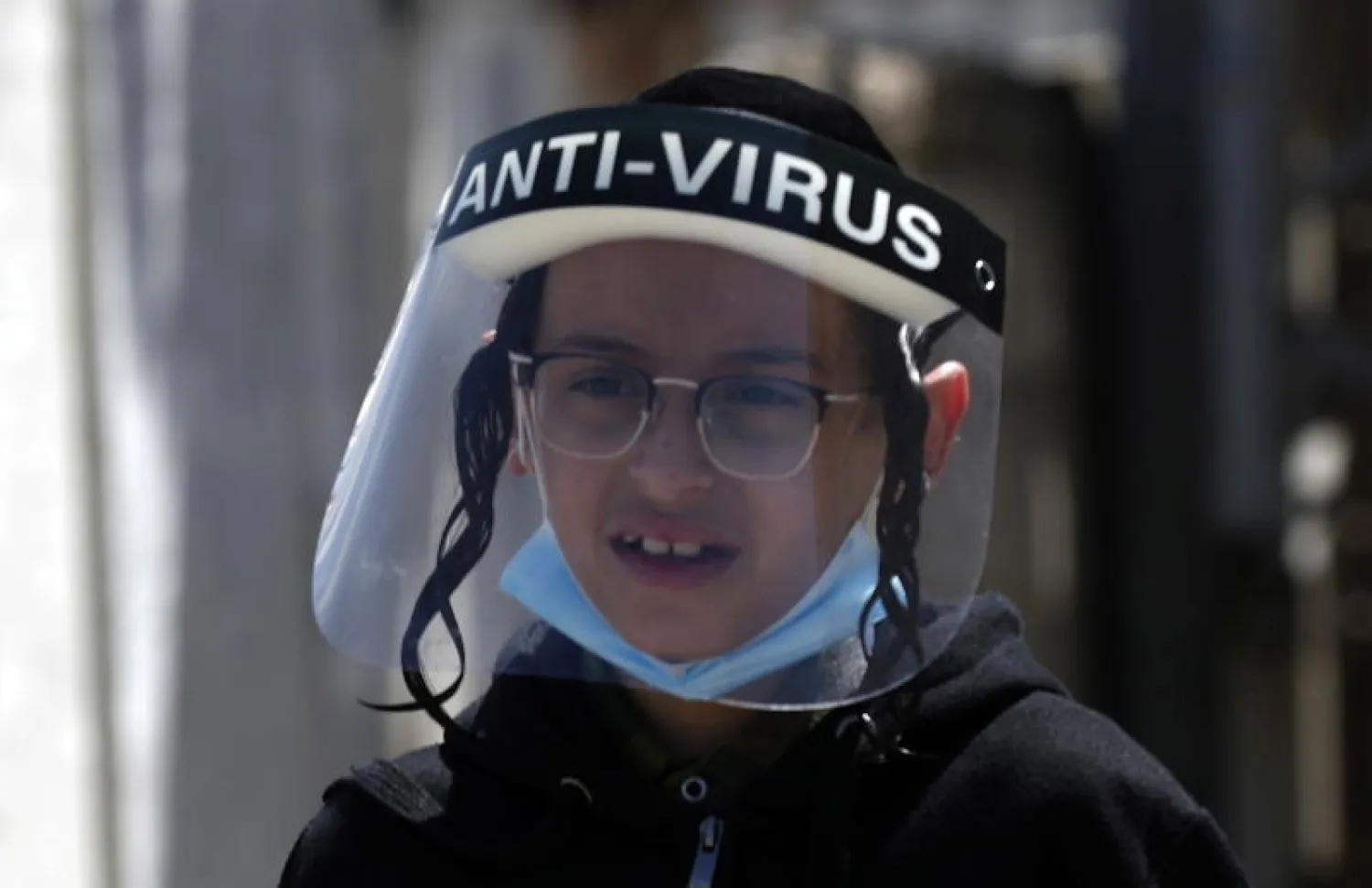 طفل إسرائيلي يرتدي قناعا بلاستيكيا واقيا خوفا من فيروس كورونا (إ.ب.أ)