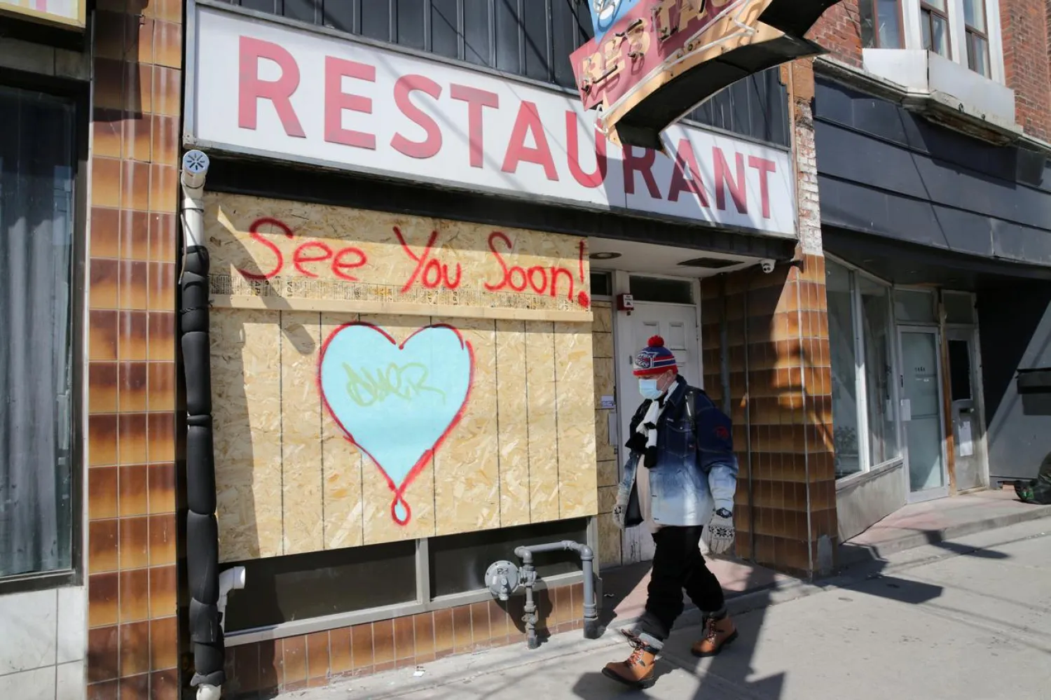 A man wearing a protective face mask passes a boarded up restaurant during the global outbreak of the coronavirus disease (COVID-19) in Toronto, Ontario, Canada April 6, 2020. (Reuters)