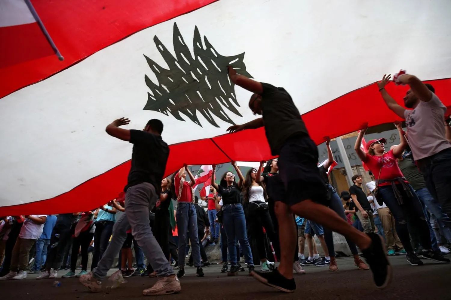 Demonstrators carry national flags during an anti-government protest in downtown Beirut, Lebanon October 20, 2019. REUTERS/Ali Hashisho
