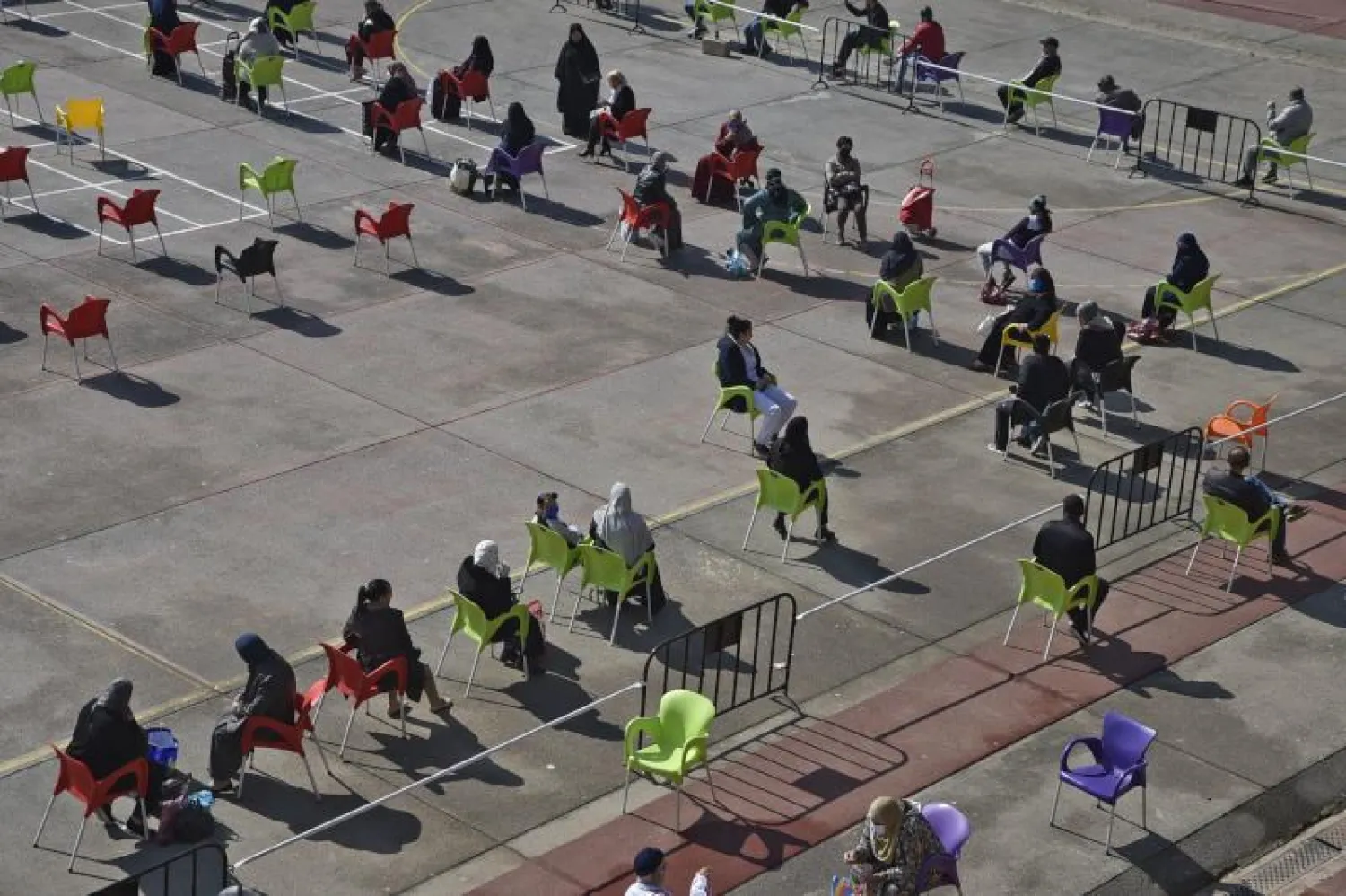 متسوقون يجلسون على مقاعد متباعدة انتظارًا لدورهم في الجزائر العاصمة (أ.ف.)