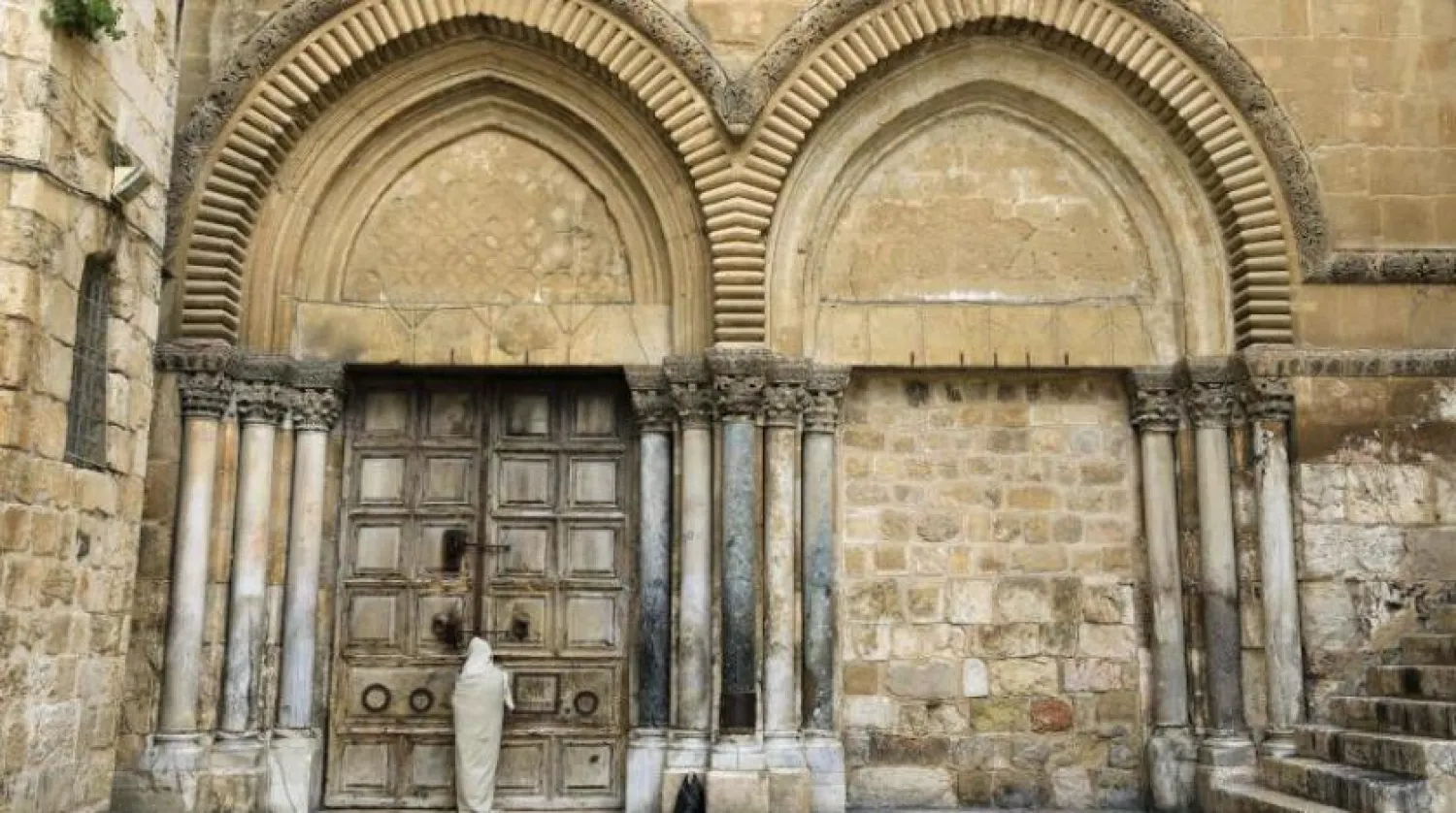 مردی پشت در بسته کلیسای قیامت در قدس ایستاده است


