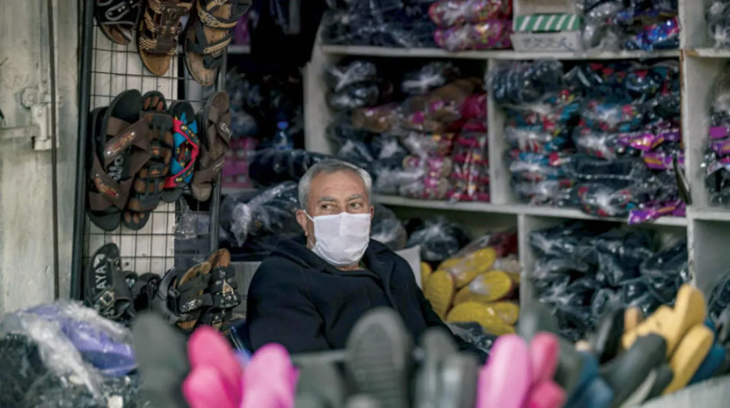 بائع يرتدي كمامة للوقاية من فيروس «كوفيد-19» في القامشلي شمال سوريا (أ.ف.ب)