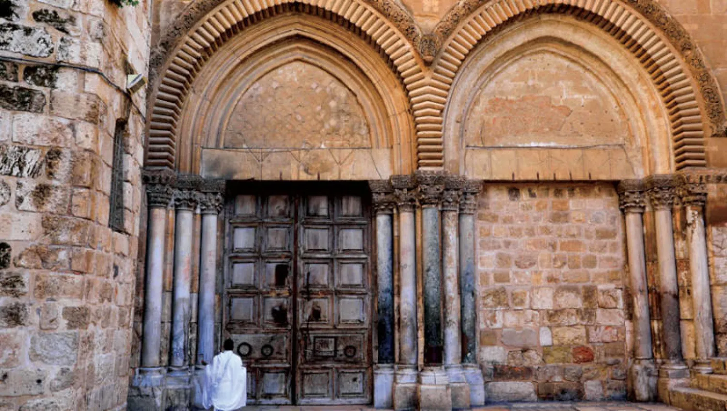 مصلٍ أمام باب كنيسة القيامة المغلق بسبب تفشي «كورونا» في البلدة القديمة بالقدس (أ.ف.ب)