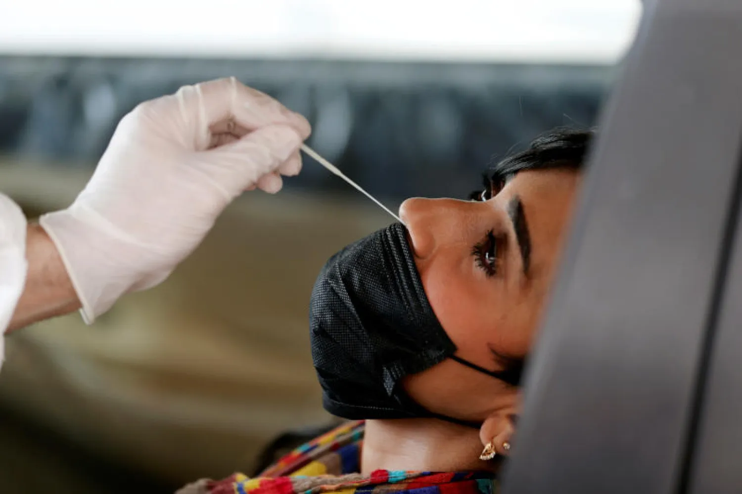 ممارس صحي يأخذ عينة من امرأة أثناء اختبار الإصابة بفيروس كورونا (رويترز)