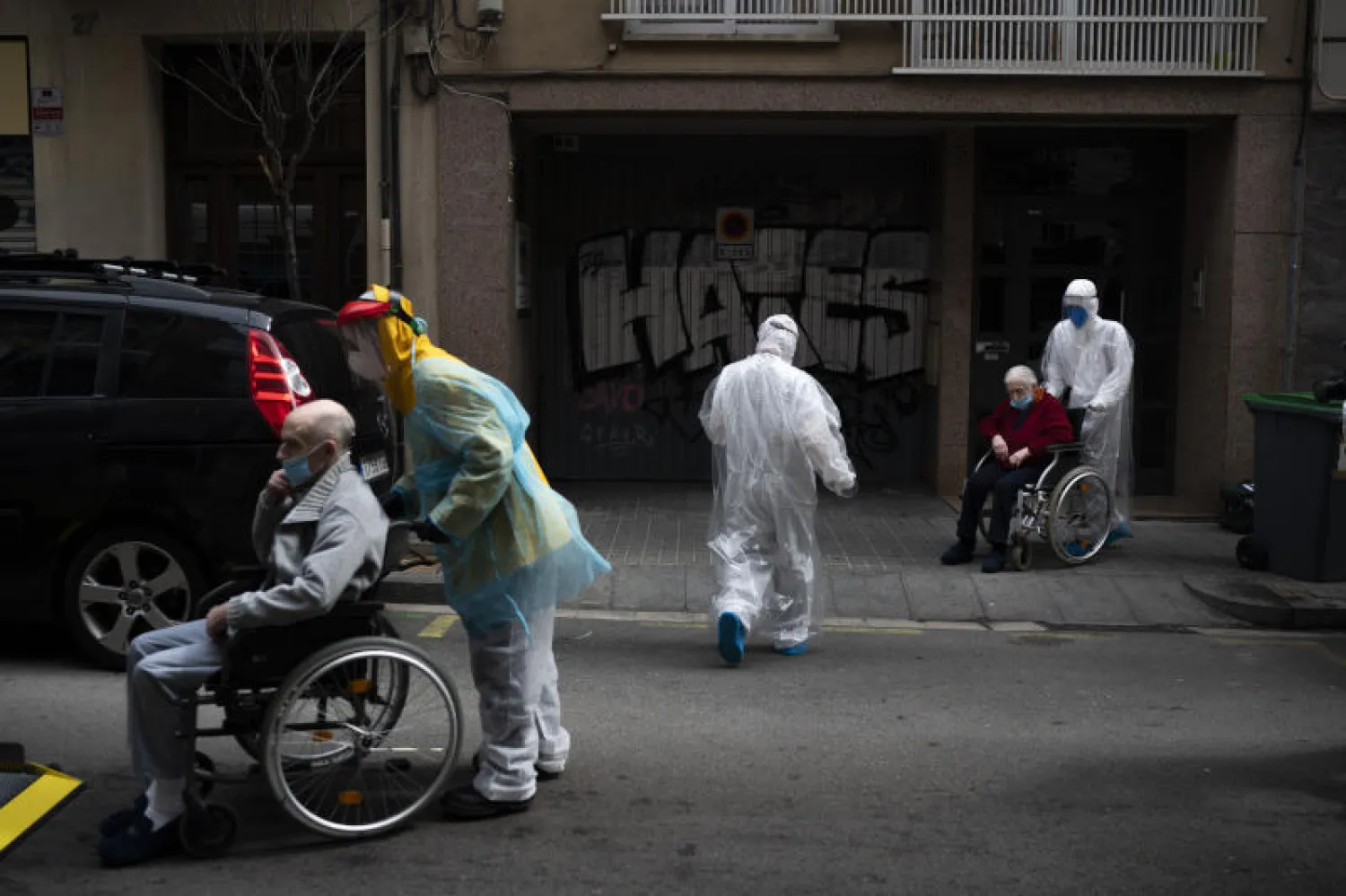 متطوعون وممارسون صحيون يقدمون الرعاية لسكان دار المسنين الذين يعانون من أعراض فيروس كورونا في برشلونة (أ.ب)