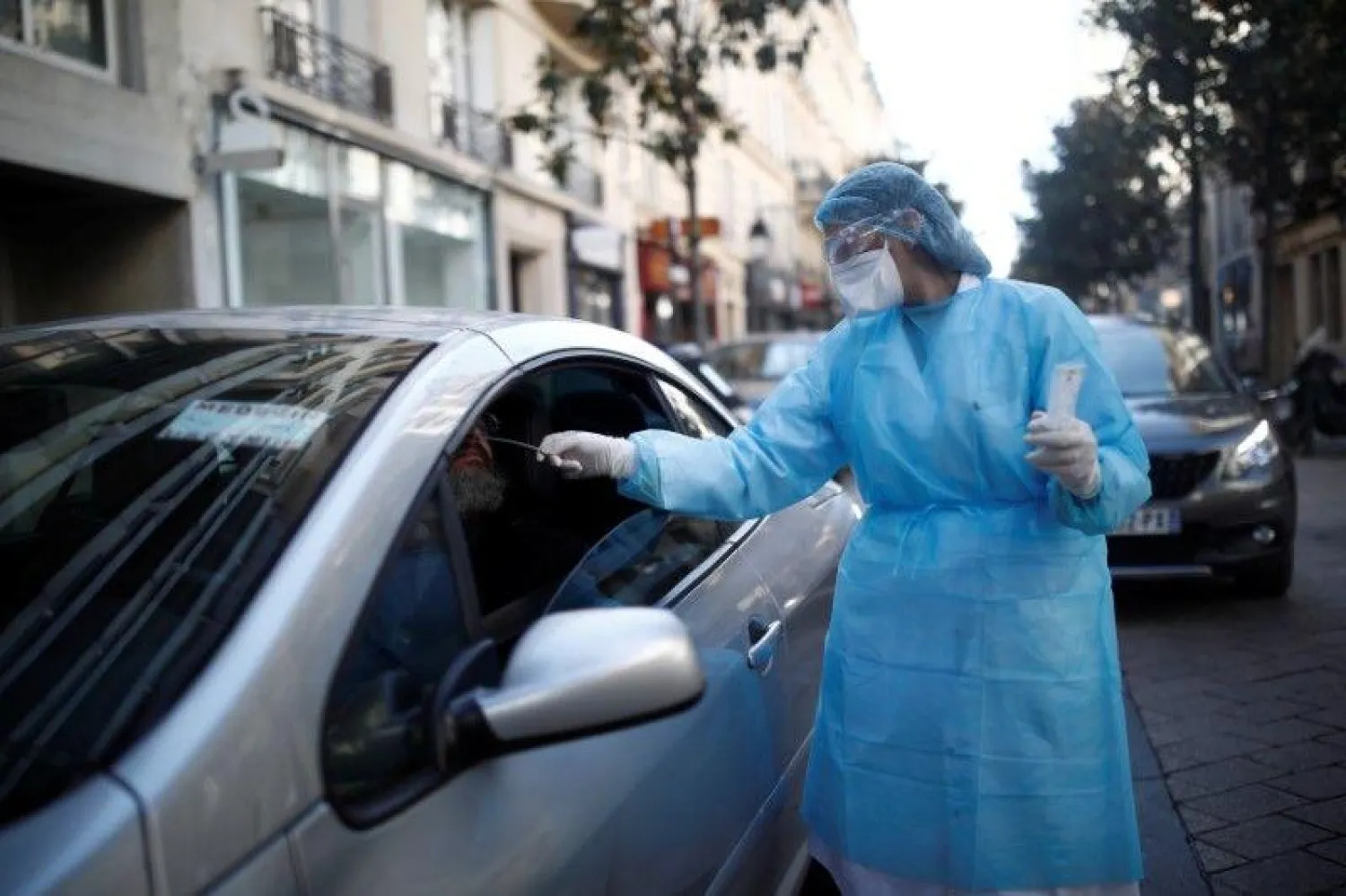 طبيبة فرنسية تقيس درجة حرارة سائقي السيارات في باريس (رويترز)