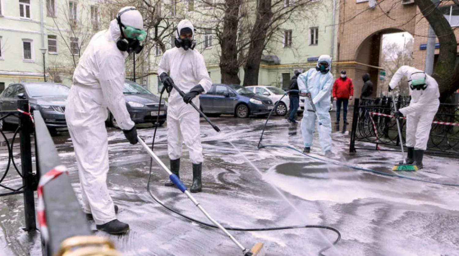 عمال بلدية موسكو يعقمون أحد شوارعها للحد من انتشار فيروس «كورونا» في المدينة أمس (أ.ب)