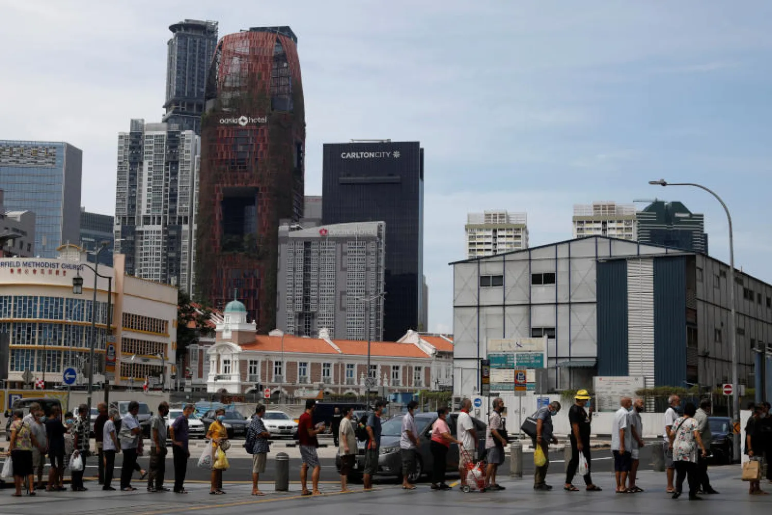 طابور من متلقّي الطعام المجاني في سنغافورة (رويترز)