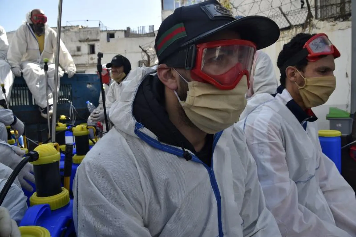 عمال البلدية يرتدون ملابس واقية أثناء قيامهم بتطهير أحد شوارع العاصمة الجزائر (أ.ف.ب)