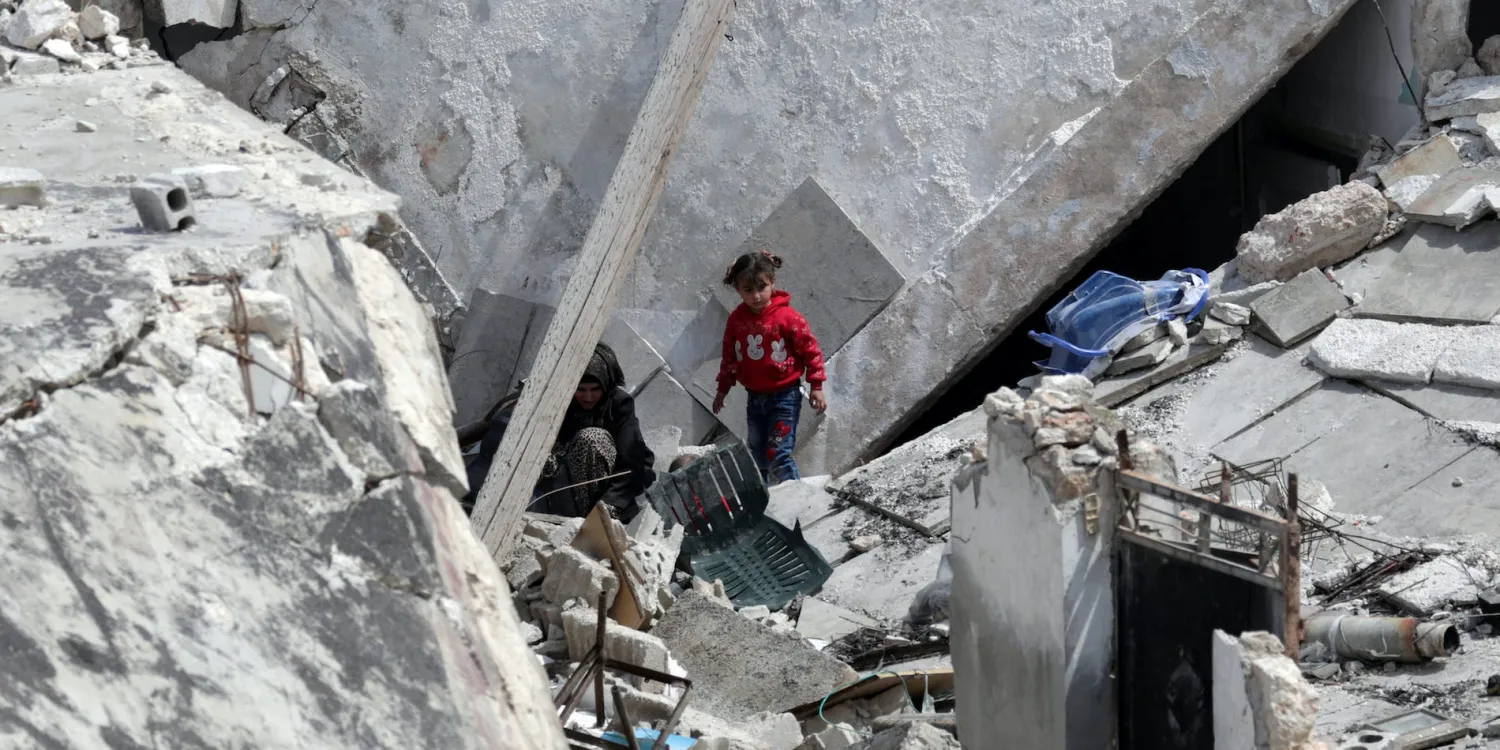 A girl stands near a woman on the rubble of a damaged building in Nairab, in northwest Syria's Idlib region, Syria April 17, 2020. REUTERS/Khalil Ashawi