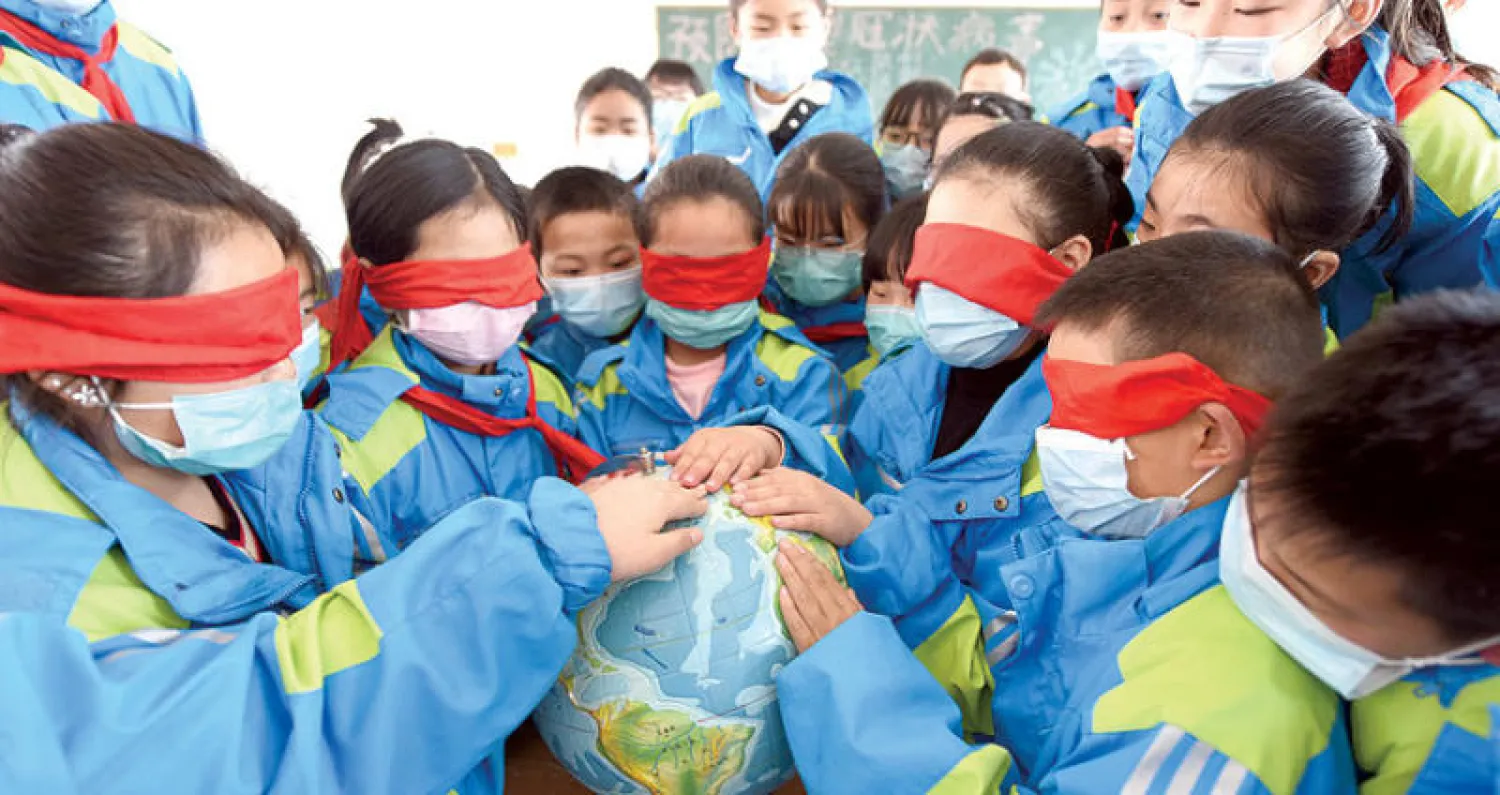 تلاميذ مدرسة ابتدائية في دونغهاي الصينية يرتدون أقنعة الوجه لمنع انتشار فيروس كورونا خلال فصل دراسي للتذكير بيوم الأرض أمس (رويترز)