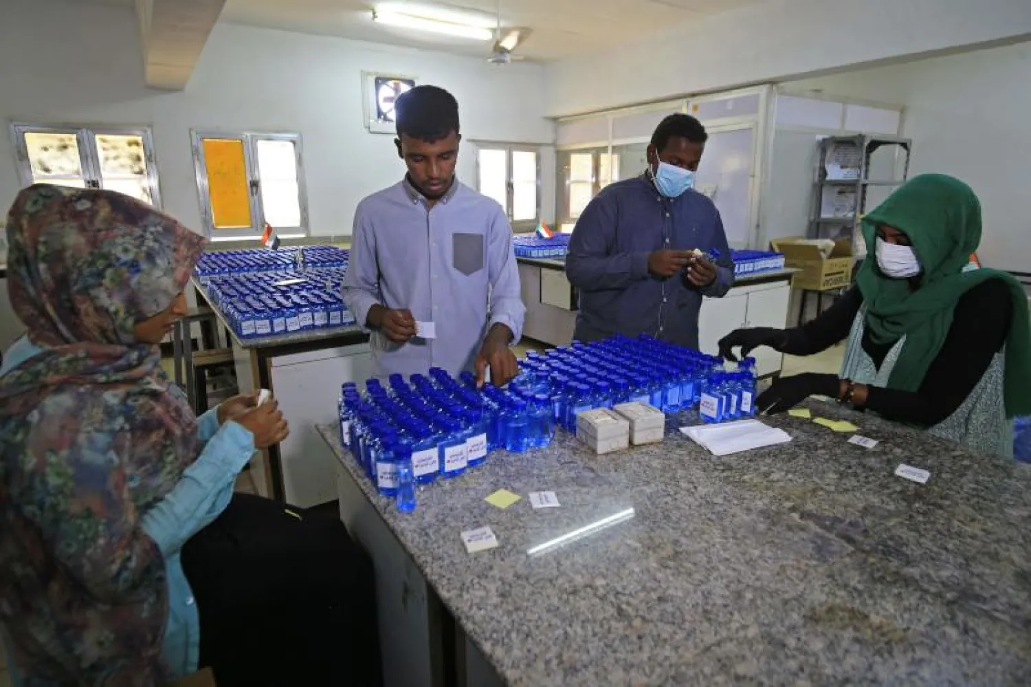 طلاب بمعمل تحاليل طبية بالخرطوم يعدّون المعقمات لمكافحة انتشار فيروس كورونا (أ.ف.ب)