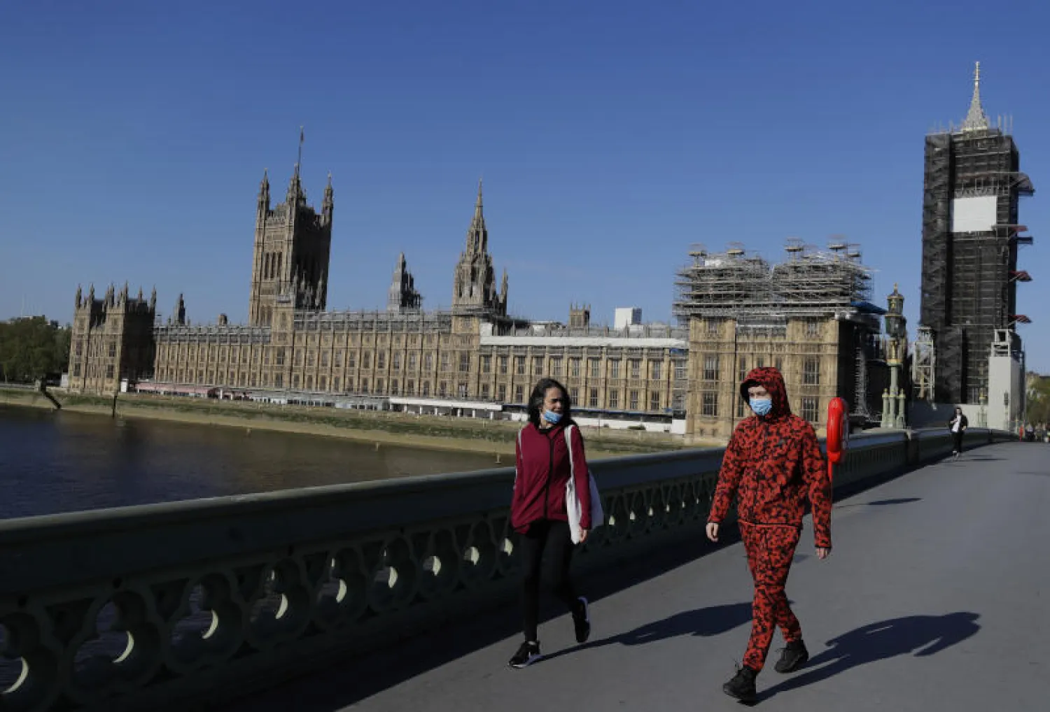 مارة يرتدون أقنعة واقية قرب مجلس العموم البريطاني خلال الإغلاق التام في البلاد (أ.ب)