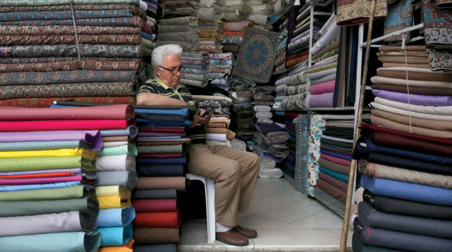 رجل يجلس بمتجره في بازار «قزوين» القديم شمال غربي طهران أول من أمس (أ.ب)