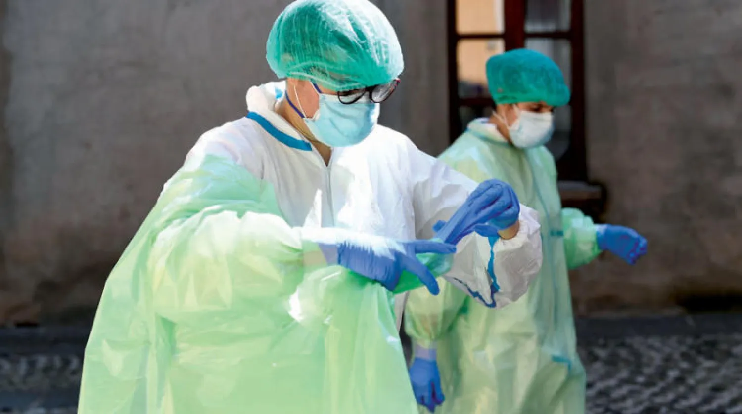 طبيبتان إيطاليتان تستعدان لزيارة دار رعاية في أوليغيو أمس (رويترز)